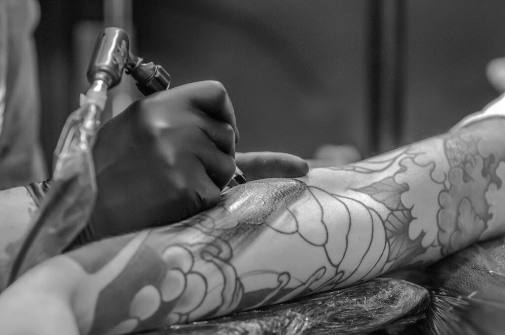 pexels-photo-955938-955938 Artistic black and white photo capturing the detailed process of tattooing an arm.